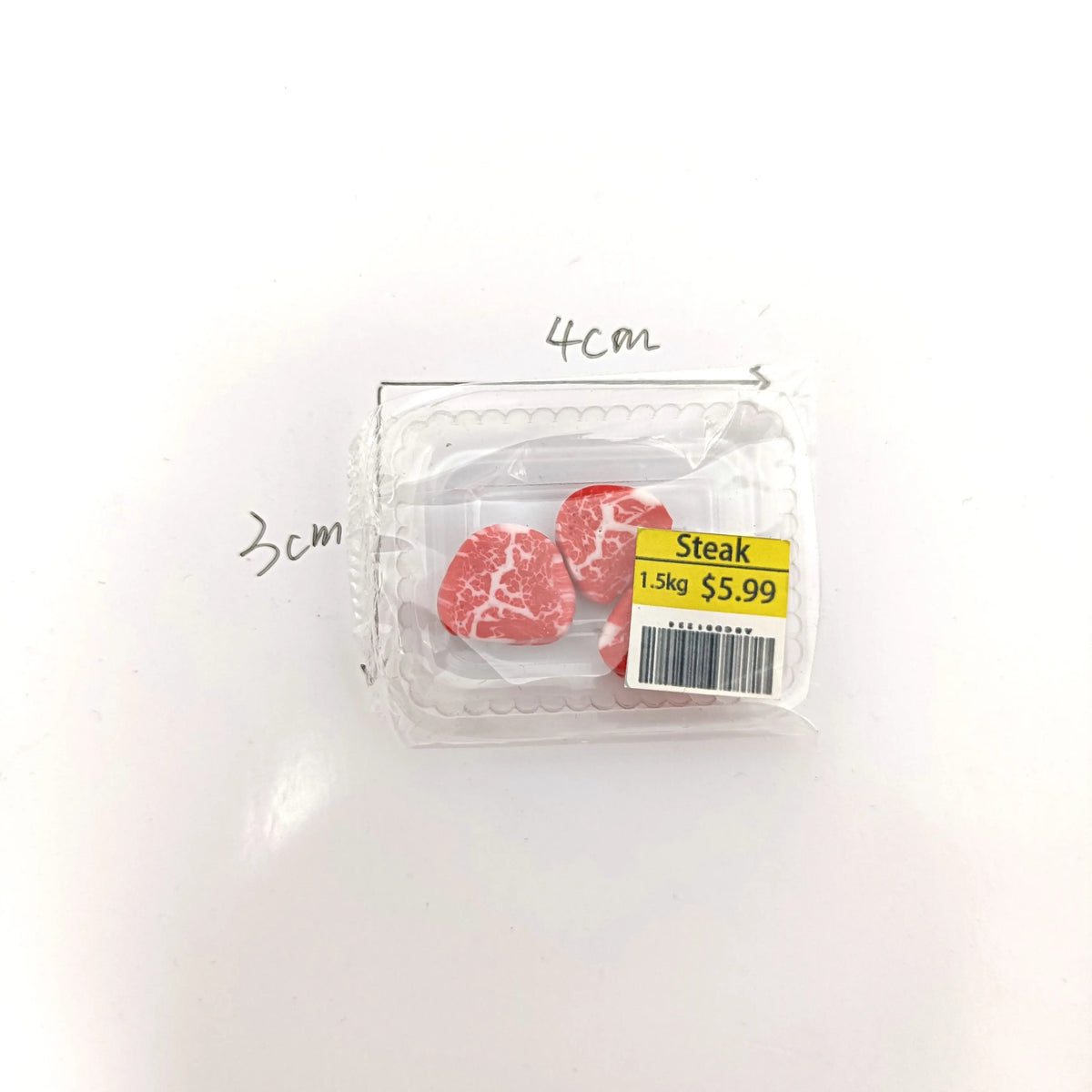 A clear plastic package containing realistic cut pieces of steak, salmon, and bacon rolls.