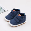 A pair of navy blue soft PU leather baby first walker shoes with anti-slip TPR soles.