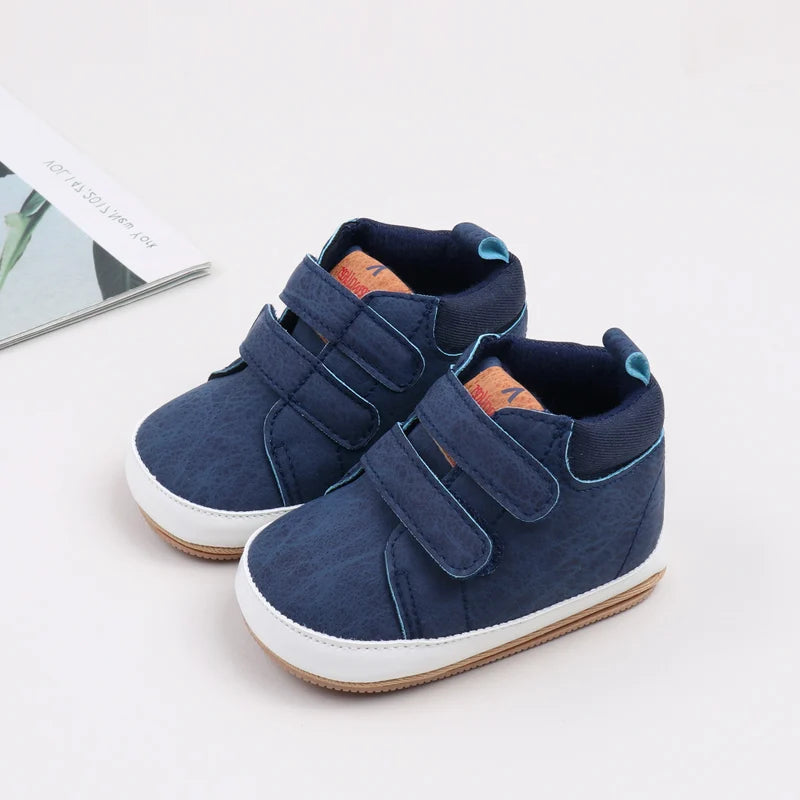 A pair of navy blue soft PU leather baby first walker shoes with anti-slip TPR soles.