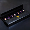 A black box holds a set of small, colorful resin polyhedral dice with a gold planetary design.