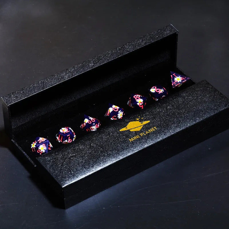 A black box holds a set of small, colorful resin polyhedral dice with a gold planetary design.