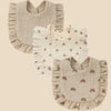 A set of three light beige cotton muslin baby bibs with ruffled edges and decorative prints.
