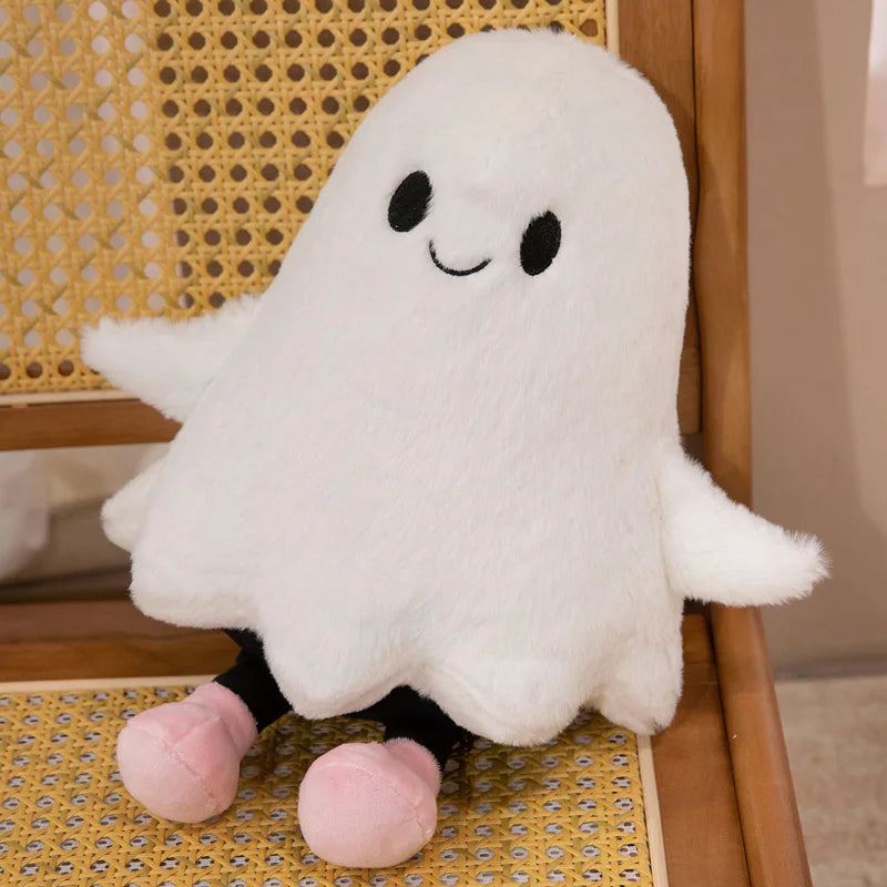 A white ghost plush toy with black accents sitting on a yellow patterned surface.