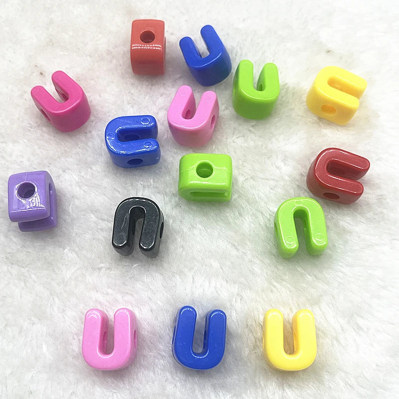 Une collection de dix perles de lettres d'alphabet mélangées dans diverses couleurs : rouge, bleu, rose, vert et jaune.