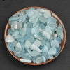 A bowl filled with light blue to pale blue translucent aquamarine chips for DIY decor or aquariums.