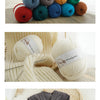 A collection of various colored wool yarn skeins and a knitted garment made from wool yarn.