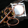 A roll of copper-colored acoustic guitar strings is shown next to a string changer tool in a silver foil packet.