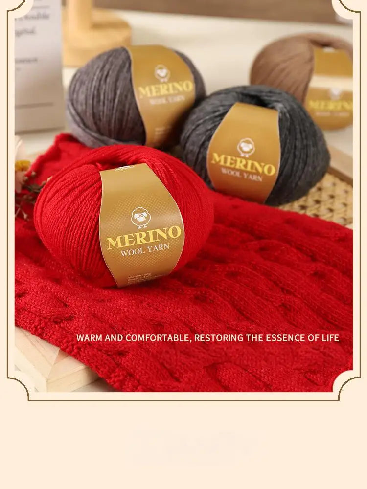 A close-up of three skeins of merino wool yarn in gray, black, and red, displayed on a textured surface.