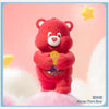 A red Care Bear plush toy with a yellow star floating above it.