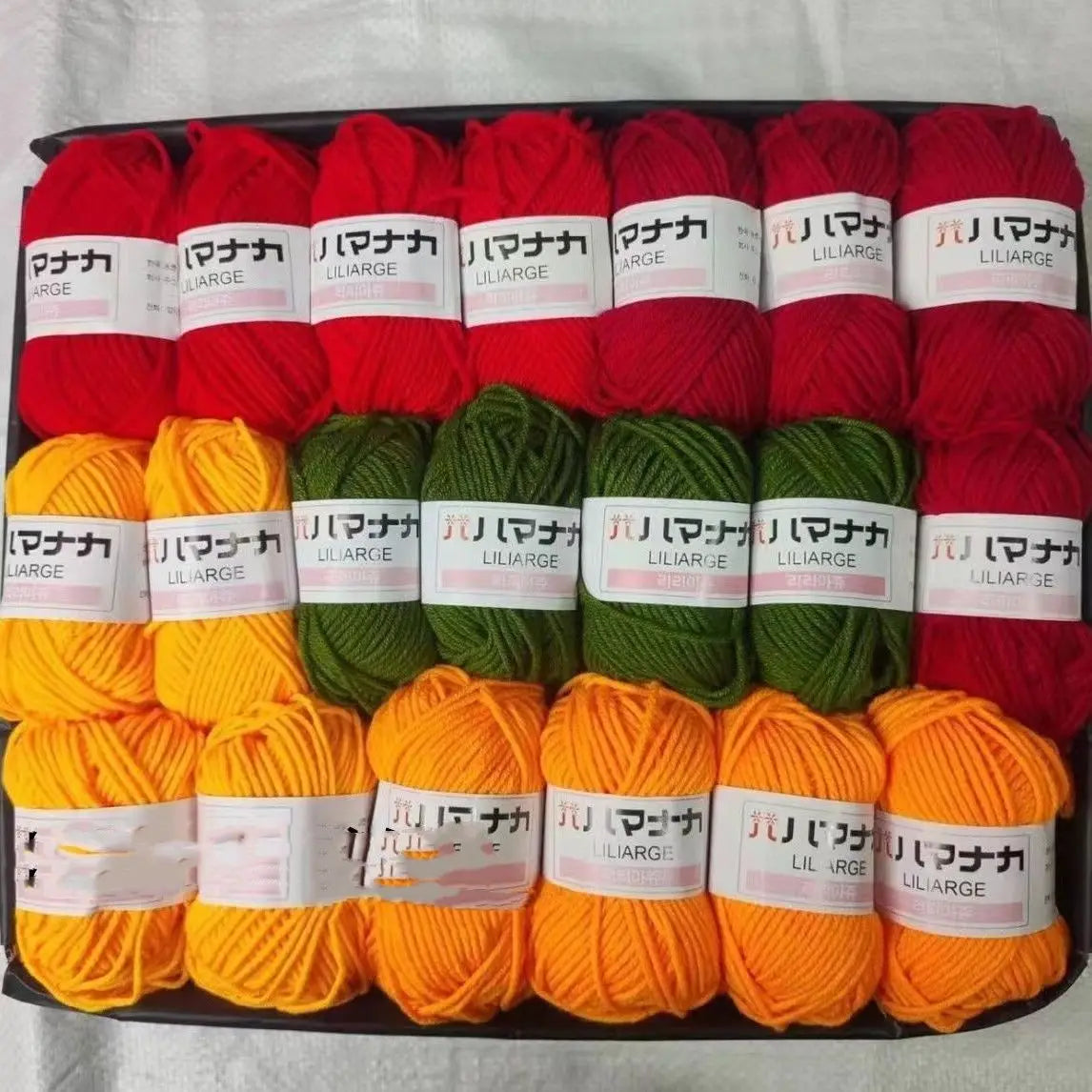 A pack of red, green, and orange acrylic yarn skeins for knitting and crochet crafts.