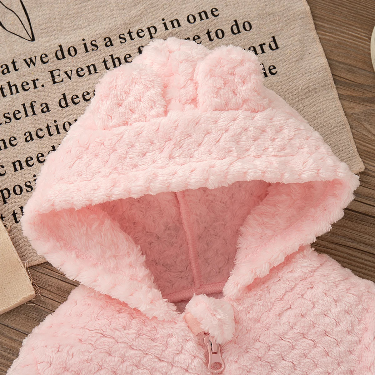 A pink fluffy plush hooded winter jacket for a baby girl