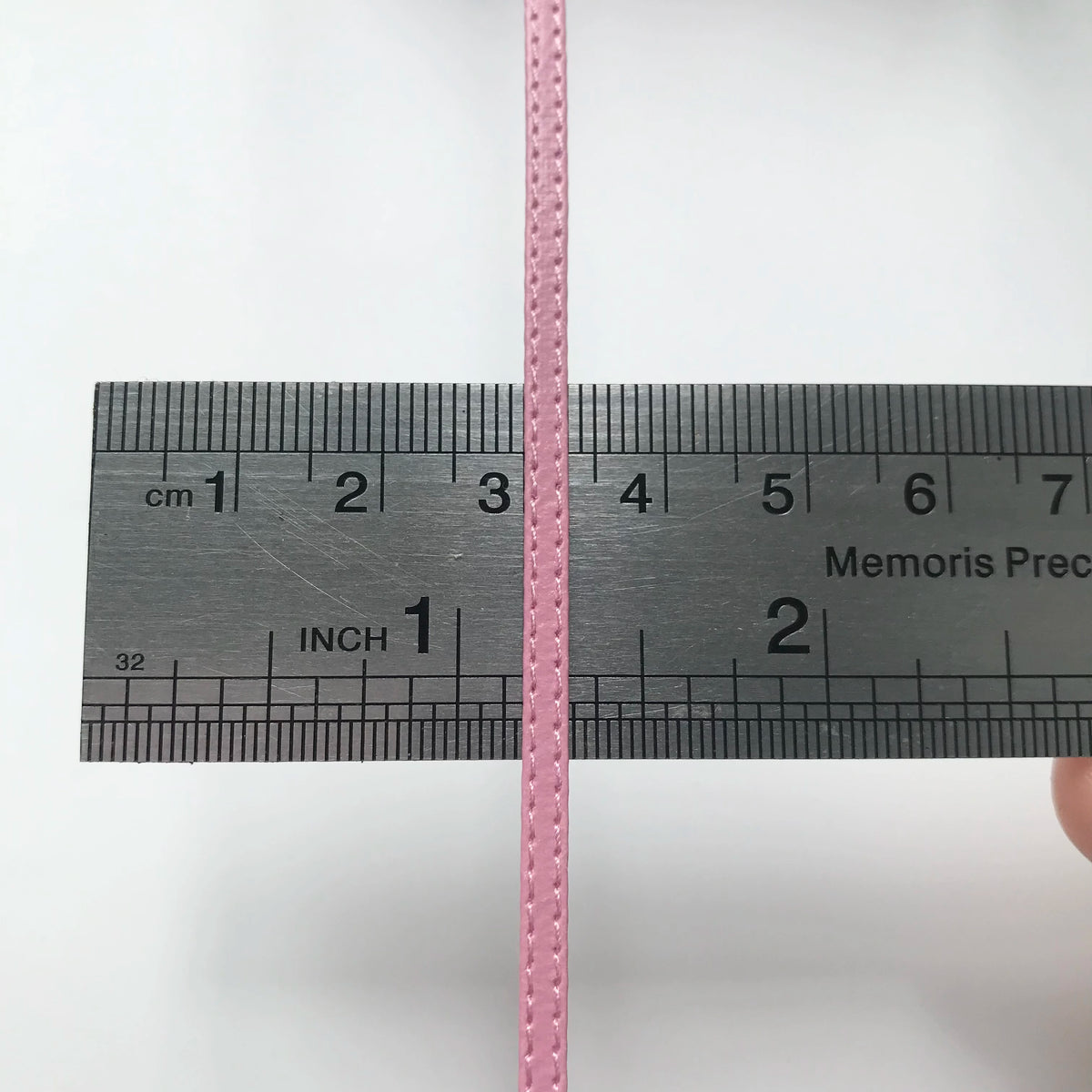 Eine rosa Messlatte kreuzt eine schwarze Lineal mit Zentimetern und Zoll markiert.