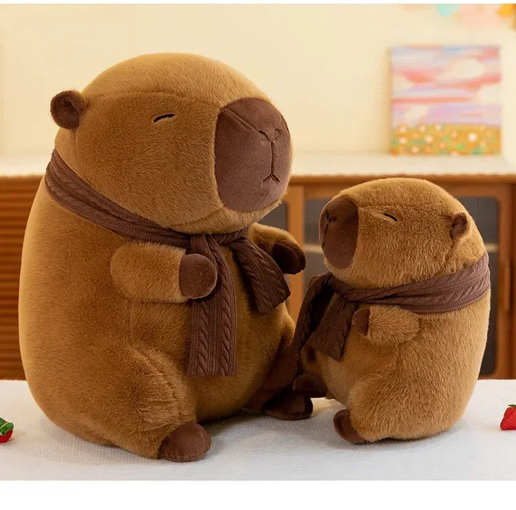 A brown plush capybara stuffed animal wearing a brown knit scarf sitting on a white surface.