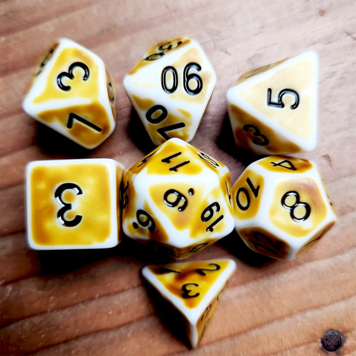 A collection of polyhedral dice, including d6 and d10 shapes, resting on a wooden surface.