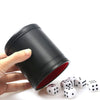 A hand holds a black leather dice cup with a red lining and five white dice on a white surface.