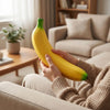 A person is holding a bright yellow banana, which is a squishy stress relief toy, while relaxing on a sofa.