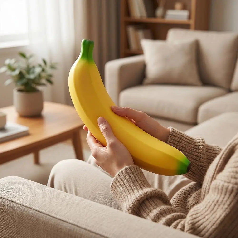 A person is holding a bright yellow banana, which is a squishy stress relief toy, while relaxing on a sofa.