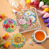 A set of floral diamond painting coasters featuring various flower designs and a metal holder with loose silk flowers.