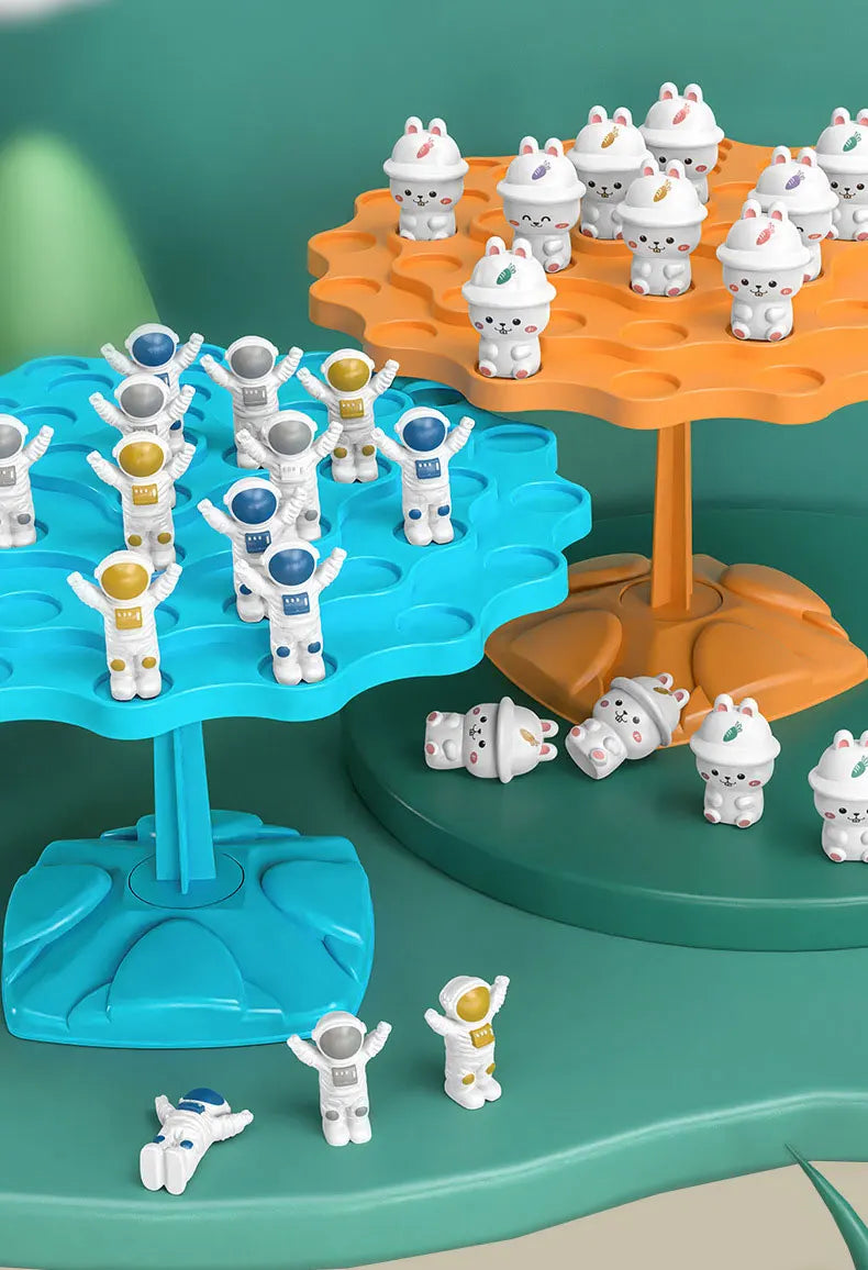A set of white frog-shaped balance toys are displayed on an orange and blue tree structure.