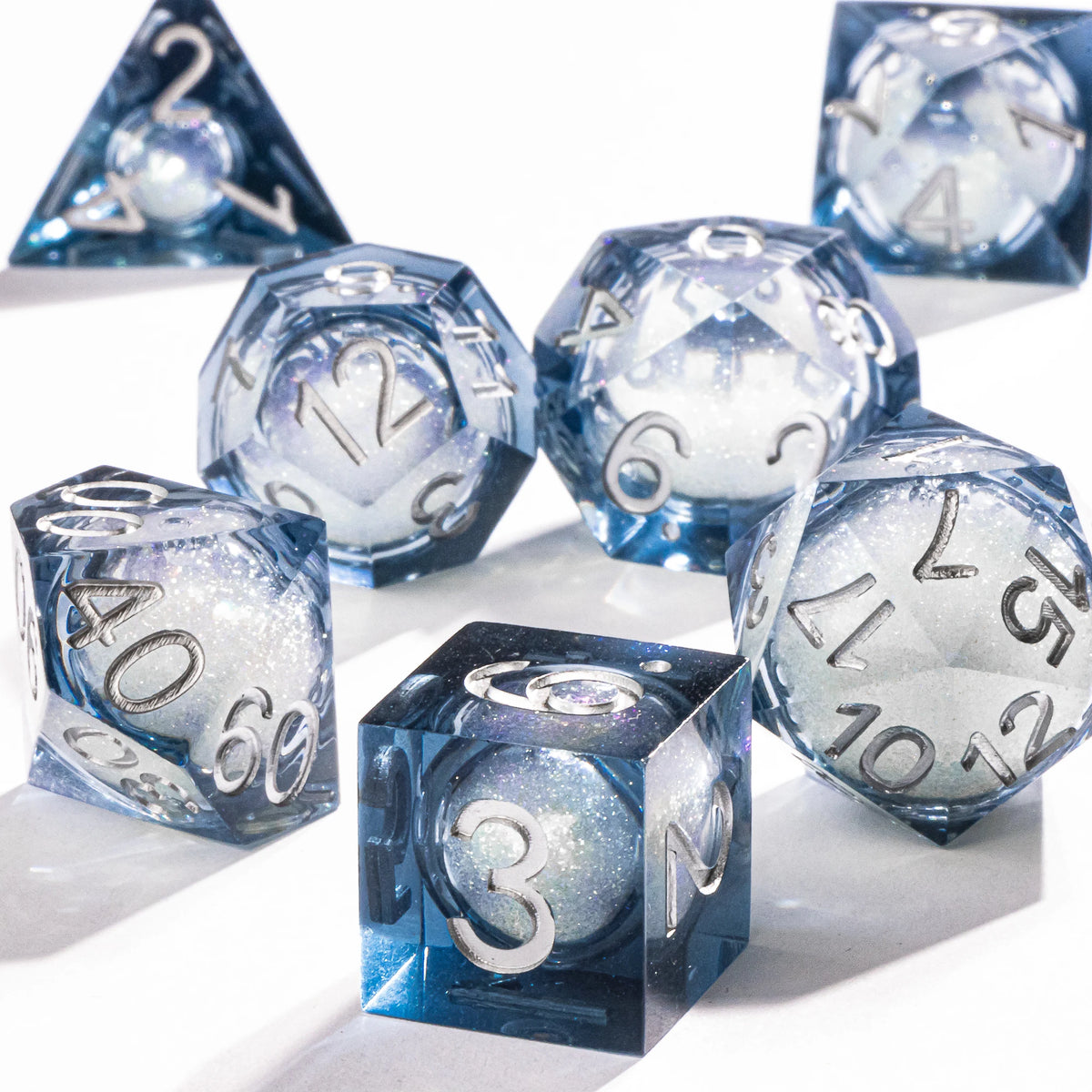 A collection of blue polyhedral dice, including a d20 and d12, with a sparkling galaxy finish.