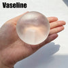 A clear, spherical Vaseline fidget ball is held in a person's hand against a bright background.