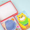 A red box containing a Montessori wooden bear feeding game with various food items and utensils for toddlers.