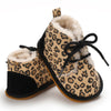 A pair of leopard print soft sole baby sneakers with black laces and fuzzy lining.