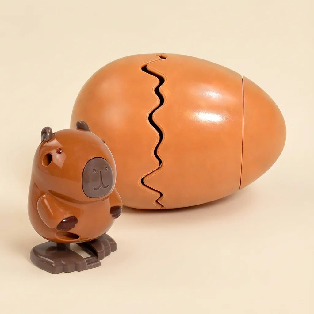 A brown wind-up bouncing chick toy with a cracked shell is shown next to its outer casing.