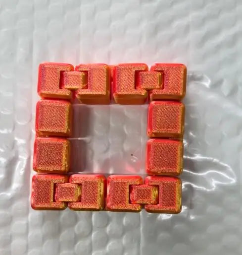 A bracelet made of orange fidget cubes with interlocking plastic links.