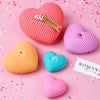 A set of pink and purple silicone heart candle molds for DIY crafting displayed on a pink background.