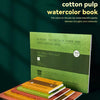 A stack of watercolor paper pads and a green watercolor book are displayed on a dark surface.