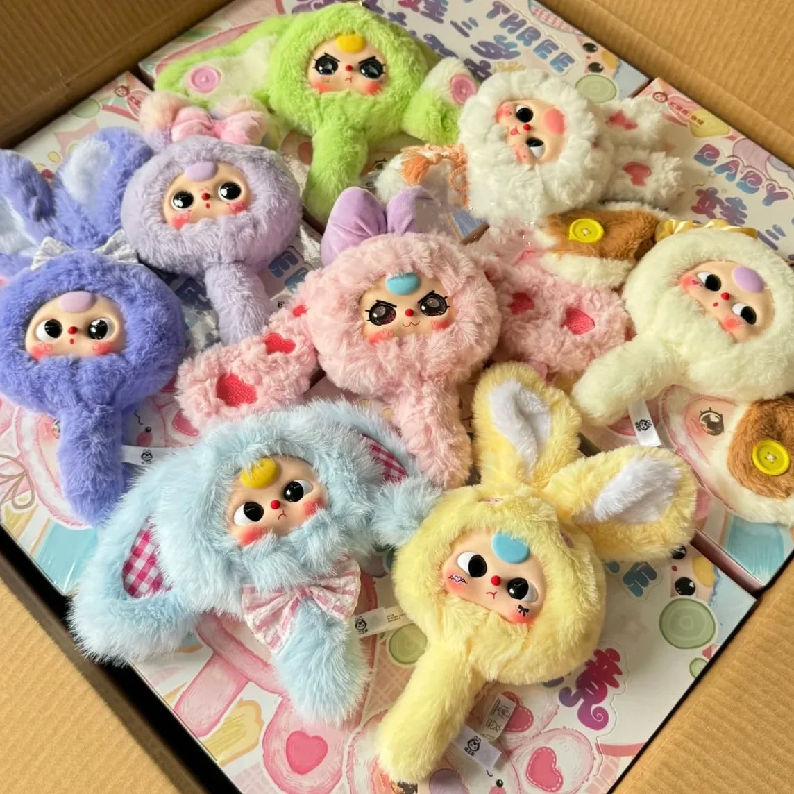 A collection of fuzzy baby figures in various colors and styles packaged in a box.