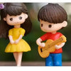 A pair of musical couple figurines, a girl and a boy, in yellow and red clothing.