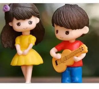 A pair of musical couple figurines, a girl and a boy, in yellow and red clothing.