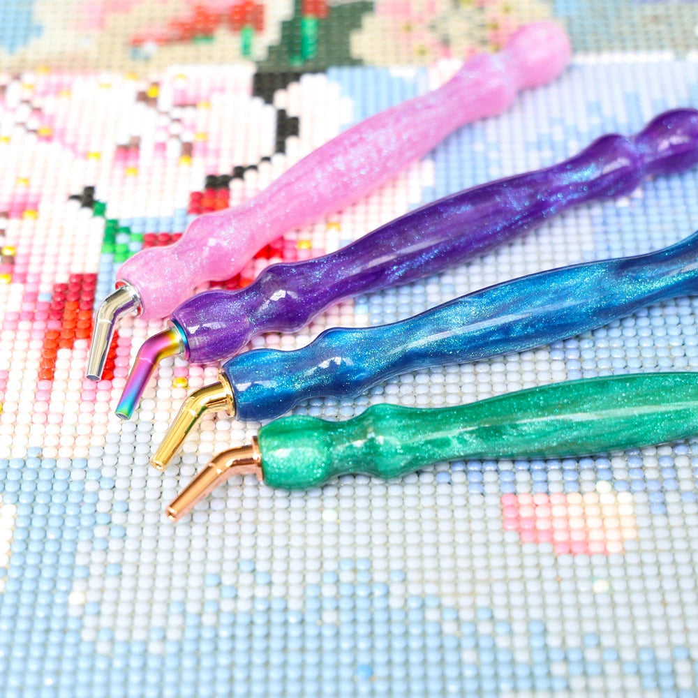 A set of colorful resin diamond painting pens with threaded dotting tips displayed on a light blue surface.