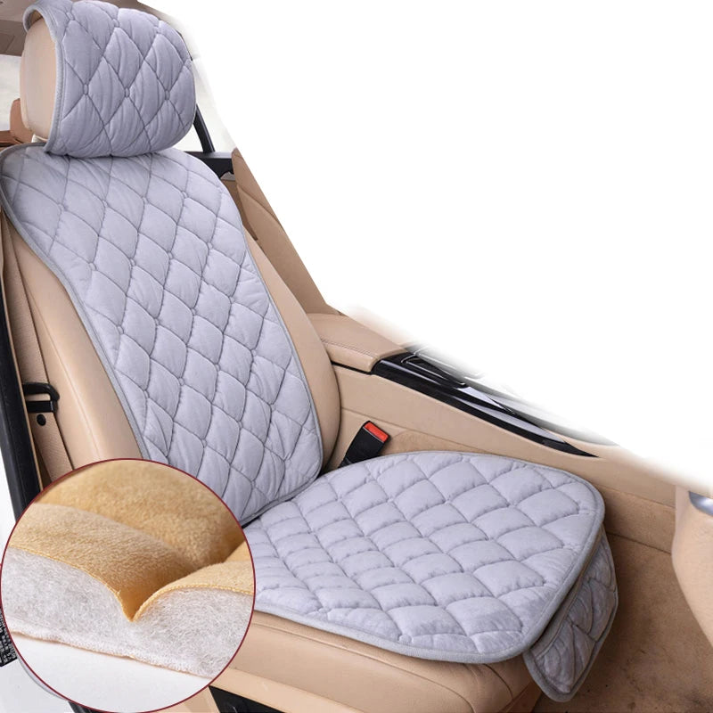A light gray quilted car seat protector with a yellow foam backing shown inside a car seat.