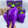 A hand holds a large purple squishy grape toy with a green stem, next to its packaging.