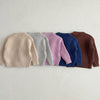 A row of nine soft cotton knit baby pullover sweaters in pastel and earthy tones laid out horizontally.