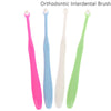 A set of four orthodontic interdental brushes in pink, blue, white, and green.