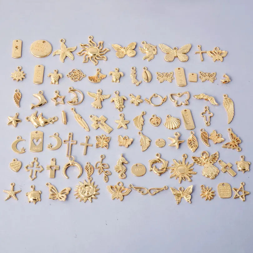 A collection of various gold-toned mixed metal charms and pendants for DIY jewelry making.
