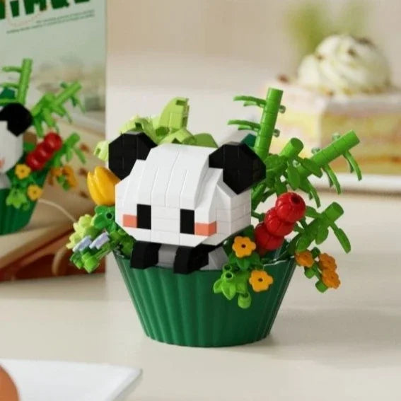 A building block set depicting a panda face surrounded by green leaves and colorful flowers in a green pot.