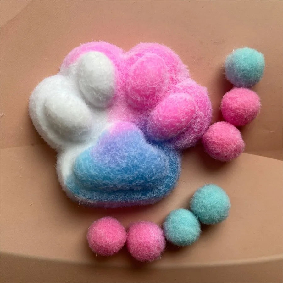 A squishy fidget toy shaped like a cat paw made of soft, pastel pink and blue mochi-like material.