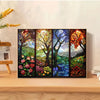 A framed stained glass art piece depicting a vibrant forest landscape with colorful trees and foliage.