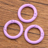 A set of ten purple metal O-ring spring clasps for DIY jewelry and keychains arranged on a wooden surface.