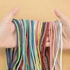 A hand holds a bundle of natural cotton macrame rope in various colors for crafts and decor.