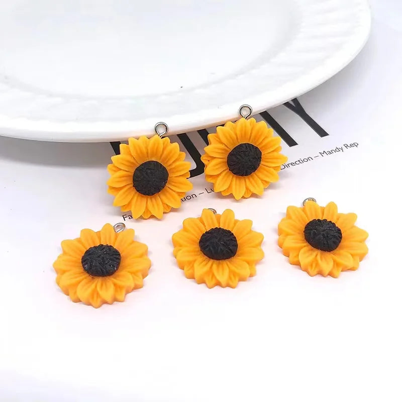 Several bright orange sunflower charms with black centers are displayed on a white plate.