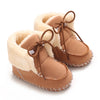 Pair of tan suede baby snow boots with fluffy shearling lining and brown laces