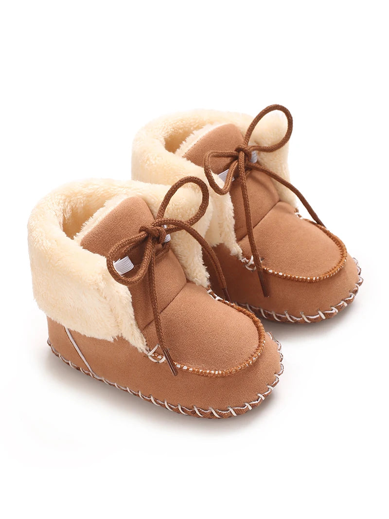 Pair of tan suede baby snow boots with fluffy shearling lining and brown laces