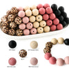 A collection of soft food-grade silicone beads in various colors including black, pink, and brown, arranged on a white platte