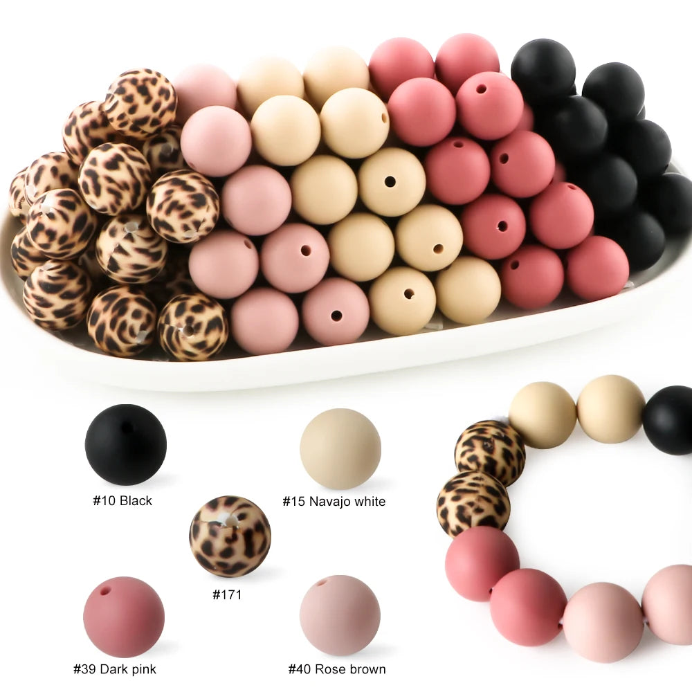A collection of soft food-grade silicone beads in various colors including black, pink, and brown, arranged on a white platte